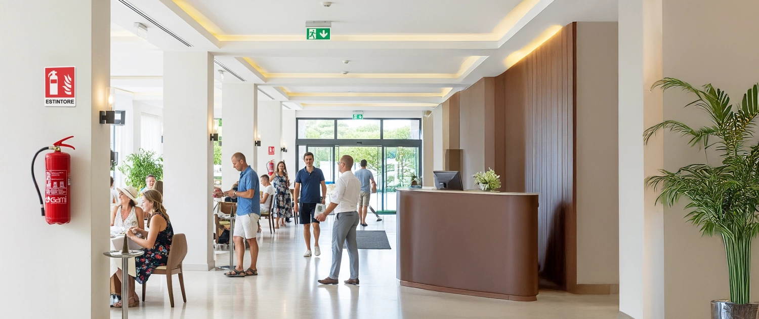 Sicurezza antincendio per strutture turistiche 1 Hall di un albergo con turisti e dispositivi antincendio come estintori, rilevatori di fumo e segnaletica di sicurezza